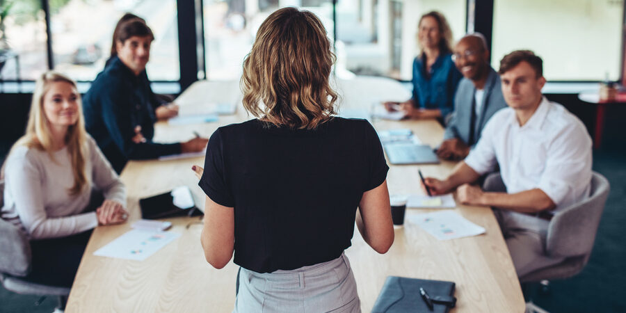 Rear view of a businesswoman addressing a meeting in office. Female manager having a meeting with her team in office boardroom.